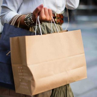 Fotografia do braço de uma mulher segurando uma sacola de compras